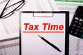 The inscription tax time is written in red letters on the tablet against the background of reports next to glasses and a Royalty Free Stock Photo