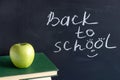 Inscription text Back to school on black chalkboard and green Apple on stack books textbooks, Concept education Royalty Free Stock Photo