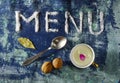 Inscription text menu made of salt with spoon, cup of milk walnuts, leaves and purple petals isolated on blue rugged backgr Royalty Free Stock Photo