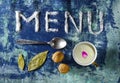 Inscription text menu made of salt with spoon, cup of milk walnuts, leaves and purple petals isolated on grungy blue backgr Royalty Free Stock Photo