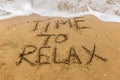 The inscription `time` on the sea sand with the incoming wave. Sandy beach with waves.