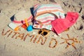 Inscription vitamin D, shape of sun and accessories for relax on sand at beach. Prevention of vitamin D deficiency and healthy Royalty Free Stock Photo