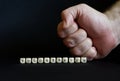 Inscription voluntarism and a clenched male fist on a black background. The concept of voluntaristic oppression, coercion and lack