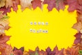 Inscription of wooden blocks hello autumn. Frame made of red and orange autumn maple leaves on a bright yellow Royalty Free Stock Photo