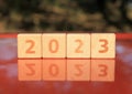 Inscription 2023. Wooden square cubes and numbers on red (orange) metal surface means coming New Year Eve