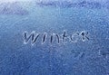 Inscription the word winter scraped on the frosty glass covered with white crystals and painted on the car window on a winter cold Royalty Free Stock Photo