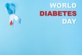 Inscription world diabetes day and blue ribbon awareness with red blood drop on a blue background