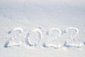 The inscription `2022` is written at the real pure white snow. New year and Christmas background