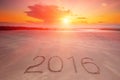 2016 inscription written in the wet yellow beach sand