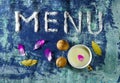 Inscryption menu with cup of milk, walnuts, bay leaves and purple petals isolated on grungy blue background Royalty Free Stock Photo