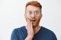 Insecure cute redhead man in glasses did not expact kiss in cheek from loving woman on date, touching face and staring Royalty Free Stock Photo