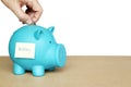 Insert coins in blue piggy bank with sticky note and wedding word on concept of saving money for wedding