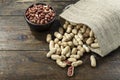 Inshell peanuts in burlap, on brown wooden background. next is a plate with peanuts. Royalty Free Stock Photo