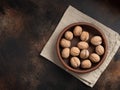 Inshell walnuts in a clay plate on a textural background. Royalty Free Stock Photo