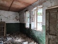 Inside an abandoned house. Scattered trash on the floor. Green paint, cracks and cobwebs on the wall. The white upper half of the Royalty Free Stock Photo