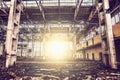 Inside abandoned large industrial warehouse hall with garbage and columns, sunset light shining through big windows Royalty Free Stock Photo