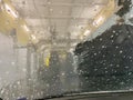 Inside automatic conveyorized tunnel car wash. View from inside car, windshield with water drops and soap foam. Royalty Free Stock Photo