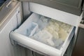 Inside of automatic ice maker with a drawer of ice cubes and plastic scoop