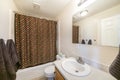 Inside a bathroom with closed brown shower curtain with colorful polka dots