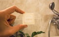 Inside the bathroom of hotel, shower andone hand of a visitor holding small piece of bathe soap from toiletries