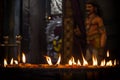 Inside Batu caves in Kuala Lumpur - flame of oil ritual sacred candles, on background of Krishna statue.