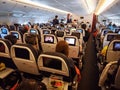 Inside the cabin of an airplane in flight with passengers seated and looking at the entertainment monitors Royalty Free Stock Photo