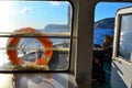 inside cabin of old yacht, ship with windows and red life buoy, white door in the light of sun in blue sea with rocks