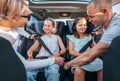 Inside car photo of mother and father fastening with safety auto belts their little daughters girl sitting in child seat and Royalty Free Stock Photo