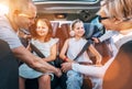 Inside car photo of mother and father fastening with safety auto belts their little daughters girl sitting in child seat and Royalty Free Stock Photo