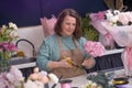 inside of charming flower shop, creative female business owner expertly arranges a stunning bouquet