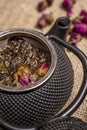 Inside closeup of an asian style black metal teapot with rose tea and green tea in the basket Royalty Free Stock Photo