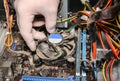 Inside details of the old personal computer. Cooler, motherboard, wires and video card in the dust. Man is holding cables in his Royalty Free Stock Photo