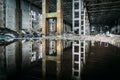 Inside of flooded dirty abandoned ruined industrial building with water reflection