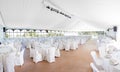Inside a large wedding tent set up for an reception with rows of tables