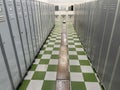 inside a locker room with rows of lockers on the sides, a wooden bench in the middle and some basins at the back, floor with green Royalty Free Stock Photo