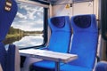 Inside of modern express train. Nobody in blue chairs at window. Comfortable chairs and table in foreground, nature outside window Royalty Free Stock Photo