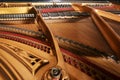 Inside an older grand piano with golden painted metal frame, strings, hammer, damper and red felt, showing the mechanics of the Royalty Free Stock Photo