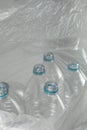 Inside an open transparent plastic bag with several empty bottles of liter and a half mineral water, without caps, just