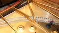 Inside of a piano with little hammer and strings