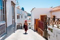 View of street inside small spanish town of Tejeda in gran canaria island with tourist woman walking on summer day with view of