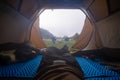 Inside the tourist tent, first person view. Foggy morning near the river. Folding chair and table. Tourism and hobby. Man legs