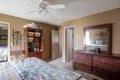 Inside view of a bedroom with a wooden cabinet, large bed, and brown walls