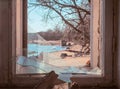 Inside view. Broken window of an old building from which you can see the beach with the bay