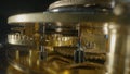 Inside view of a clockwork of golden mechanical clock on black isolated studio background. Gold gears, gearing, wheel