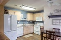 Inside view of a cozy modern kitchen with a wooden cabinet, table, chairs, and a white fridge