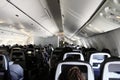 Inside view of large commercial airliner aisle with diverse passengers Royalty Free Stock Photo