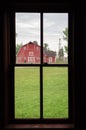 Inside view looking out at an old red barn in summertime.