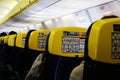 Inside view of Ryanair flight. Cabine view of the plane with flagship yellow and blue seats. Passengers seated waiting