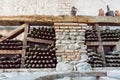 Inside a wine cellar with aged dust bottles and rustic wooden shelves. Historical storage of winery Royalty Free Stock Photo