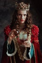 insidious medieval queen in dress pouring poison into goblet